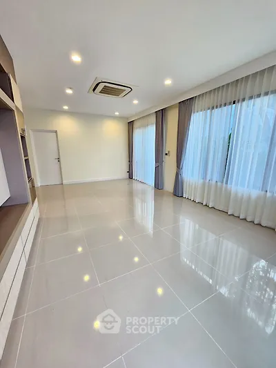 Spacious modern living room with large windows and elegant curtains, perfect for natural light.
