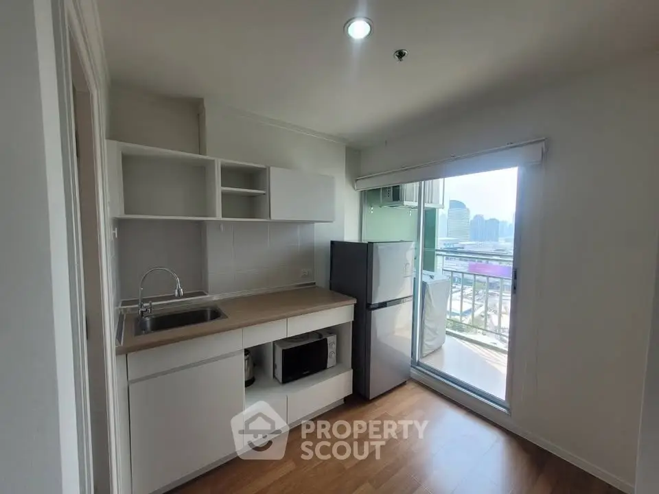 Modern kitchen with balcony view, featuring sleek cabinetry and appliances in a bright, open space.