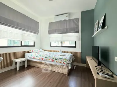 Modern bedroom with stylish decor, featuring a cozy bed, TV, and large windows for natural light.