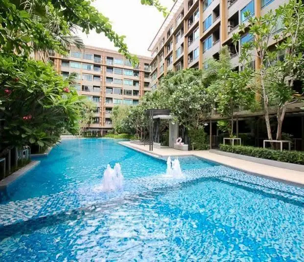 Luxurious residential building with a stunning outdoor pool and lush greenery.