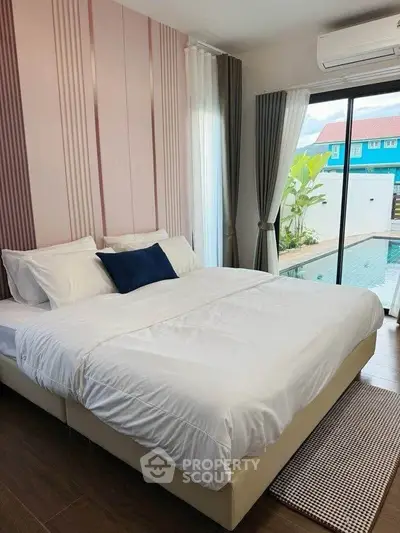 Modern bedroom with pool view, featuring elegant decor and natural light through large windows.