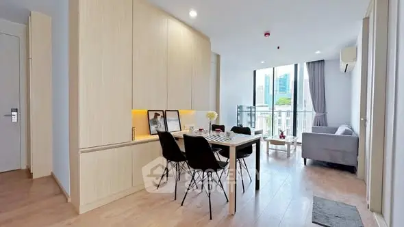 Modern living room with dining area and city view, featuring sleek furniture and natural light.