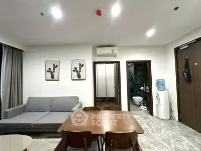 Modern living room with dining area, featuring sleek furniture and contemporary decor.
