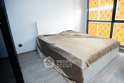 Modern bedroom with large windows and stylish bedspread in a bright apartment.
