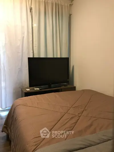 Cozy bedroom with TV and elegant curtains, perfect for relaxation.