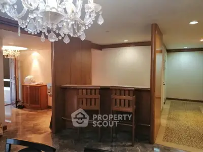 Elegant interior with wooden bar and crystal chandelier in a spacious living area.