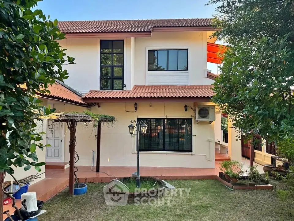 Charming two-story house with lush garden and red-tiled roof, perfect for family living.