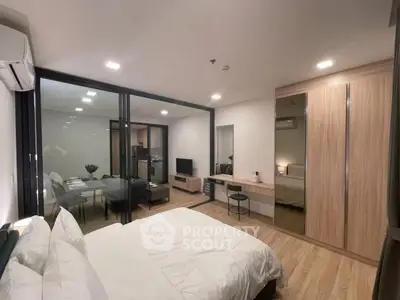 Modern bedroom with stylish decor and open layout to living area, featuring sleek furniture and ample lighting.