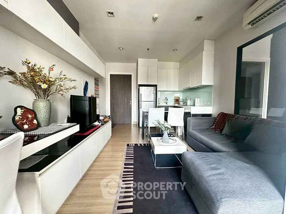 Modern living room with open kitchen, stylish decor, and cozy seating area in a contemporary apartment.