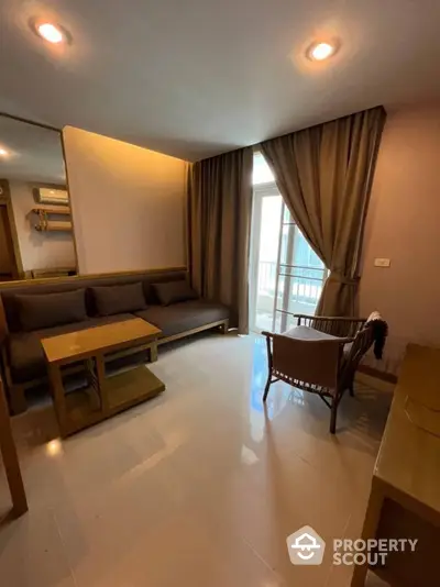 Spacious living room with glossy tiled flooring, modern recessed lighting, and elegant drapery leading to a sunlit balcony, perfect for urban living.