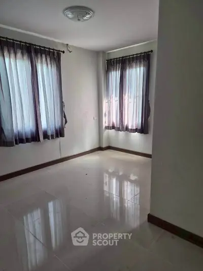 Spacious empty room with large windows and tiled flooring, perfect for customization.