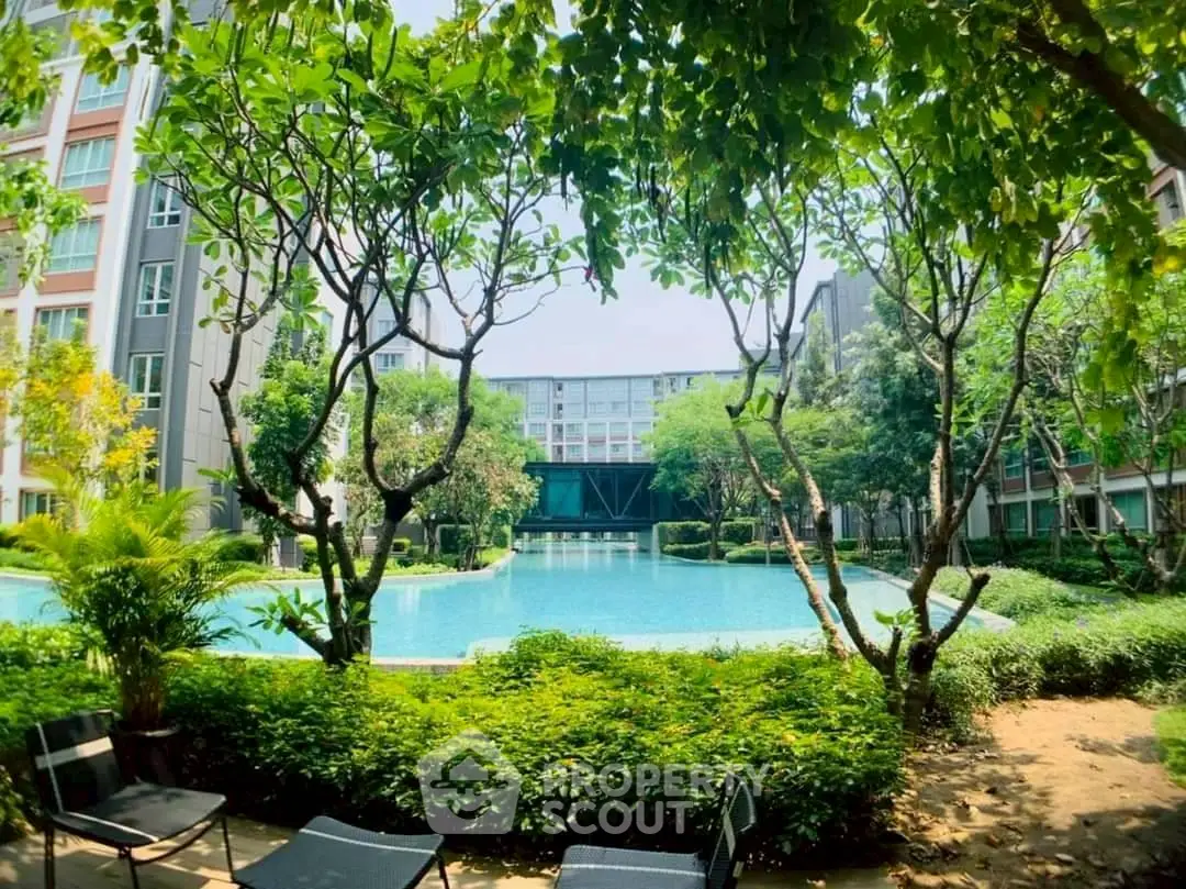 Luxurious residential pool surrounded by lush greenery and modern buildings.