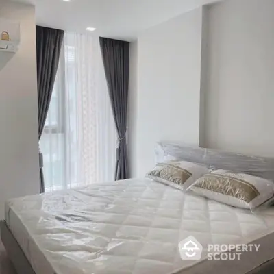 Pristine bedroom with a large bed and elegant grey curtains leading to a sunlit balcony, offering a serene and cozy ambiance.