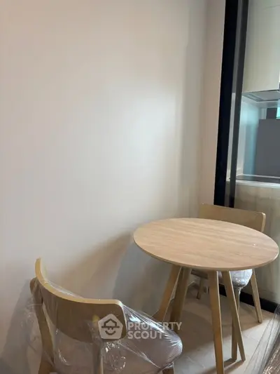 Cozy minimalist dining area with wooden table and chairs, adjacent to a modern kitchen.