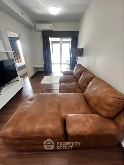 Spacious living room with leather sofa and modern decor in a stylish apartment.