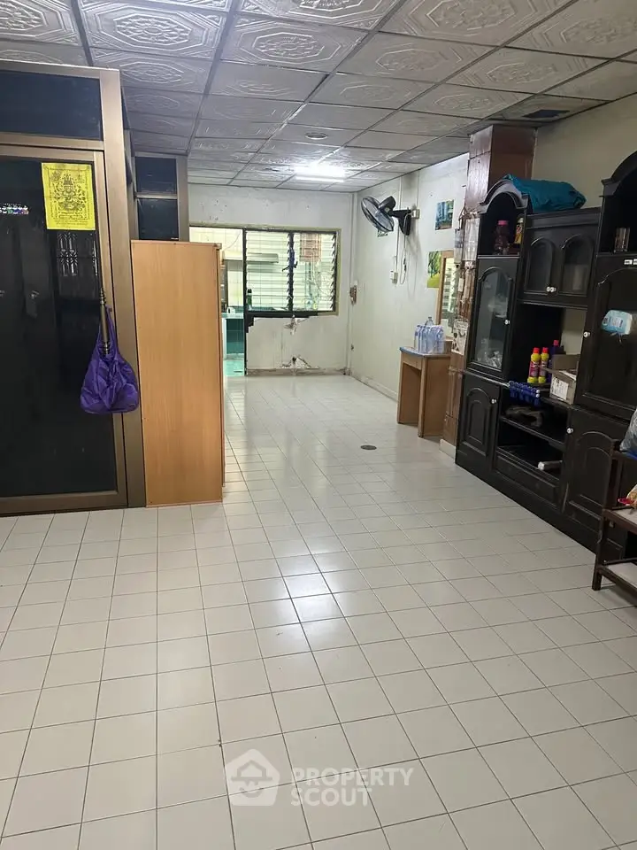 Spacious tiled living area with wooden cabinets and ample natural light, ideal for customization.