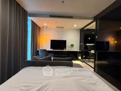 Modern bedroom with sleek design and ambient lighting, featuring a large TV and stylish furnishings.