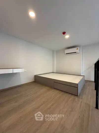 Modern minimalist bedroom with built-in bed and air conditioning, featuring sleek wooden flooring.
