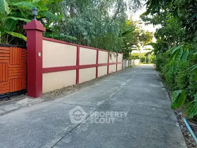Charming residential entrance with lush greenery and a secure gated pathway.