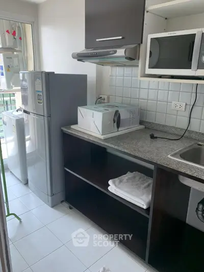 Compact kitchen with modern appliances and sleek cabinetry in urban apartment.