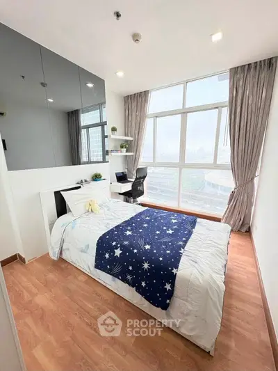 Bright bedroom with large windows and city view, featuring modern decor and cozy bedding.