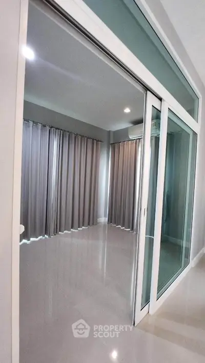 Spacious room with sliding glass doors and elegant curtains, perfect for modern living.