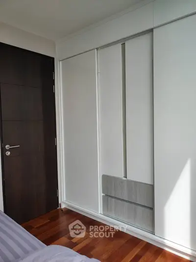 Modern bedroom with sleek built-in wardrobe and wooden flooring