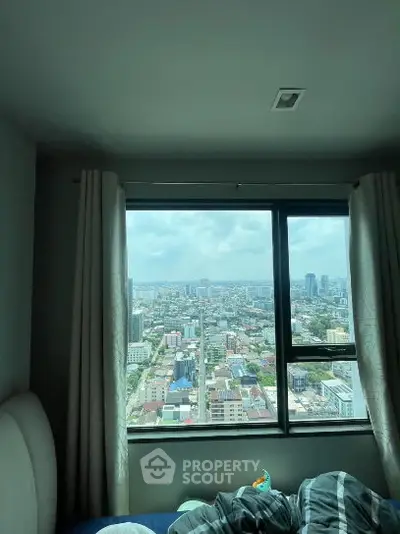 Stunning cityscape view from a cozy bedroom window in a high-rise apartment.
