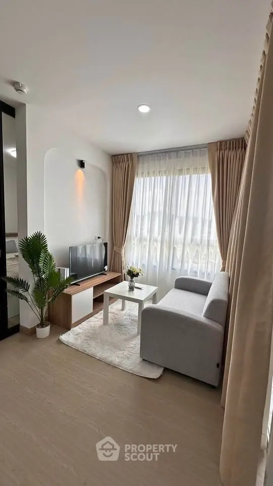 Modern living room with cozy sofa, stylish decor, and large window for natural light.