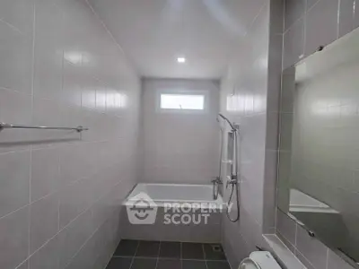 Modern bathroom with sleek tiles and bathtub, perfect for relaxation.
