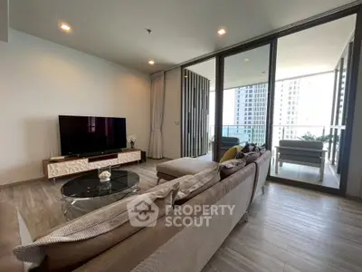 Spacious modern living room with large balcony and city view, featuring elegant decor and ample natural light.
