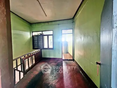 Spacious hallway with green walls and natural light, ideal for creative renovation.