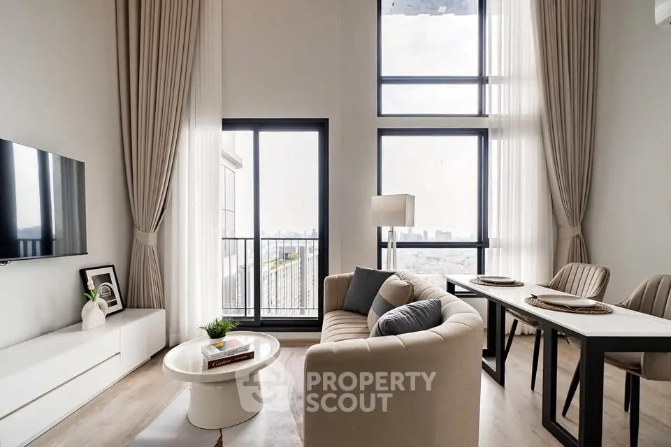 Modern living room with high ceilings and large windows offering city views.