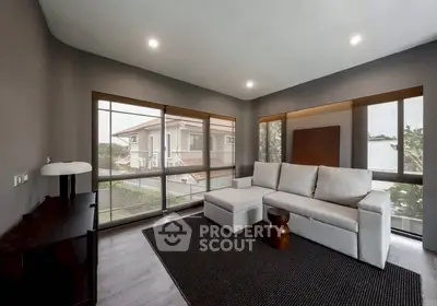 Modern living room with large windows and stylish furniture, offering a serene view of the neighborhood.