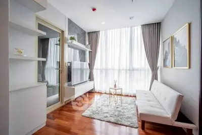 Modern living room with sleek furniture and large window, featuring hardwood floors and stylish decor.