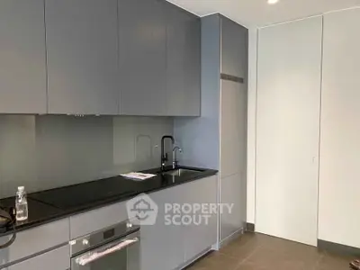 Modern kitchen with sleek cabinetry and built-in oven in a contemporary apartment.