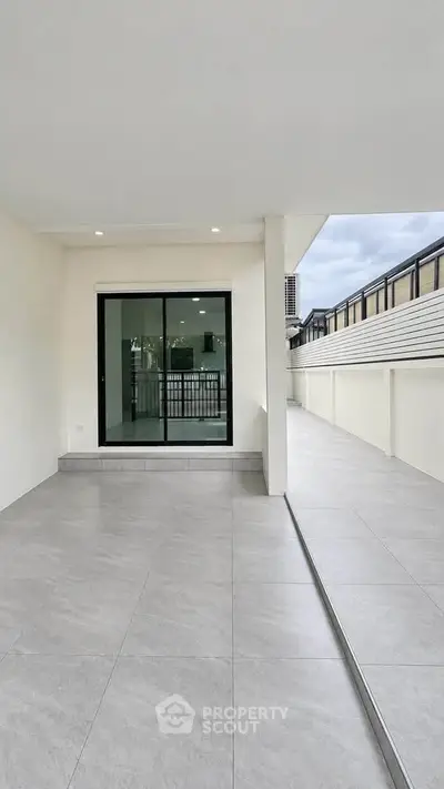 Spacious modern balcony with sleek tiles and glass doors, perfect for outdoor relaxation.