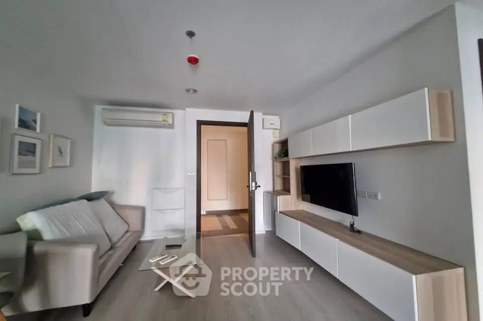 Modern living room with sleek furniture and wall-mounted TV in a stylish apartment.