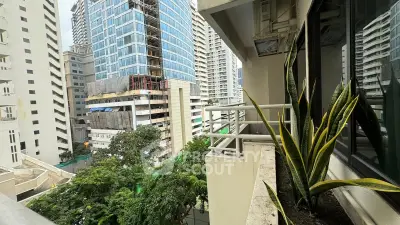 Urban balcony view with modern high-rise buildings and lush greenery