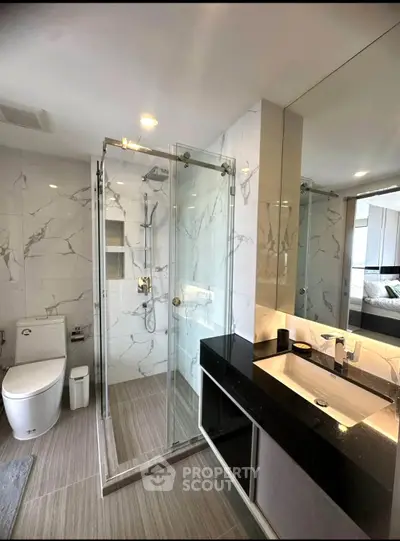 Modern bathroom with glass shower and sleek vanity in luxury apartment