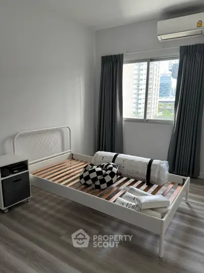 Modern minimalist bedroom with single bed frame and city view window, perfect for urban living.