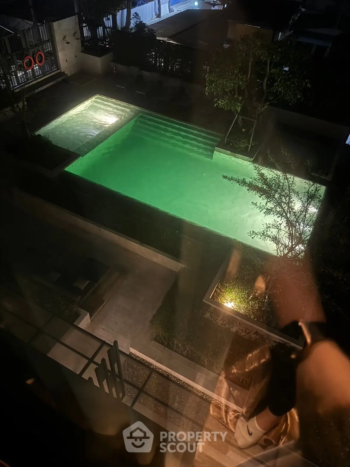 Stunning night view of illuminated swimming pool in modern residential complex.
