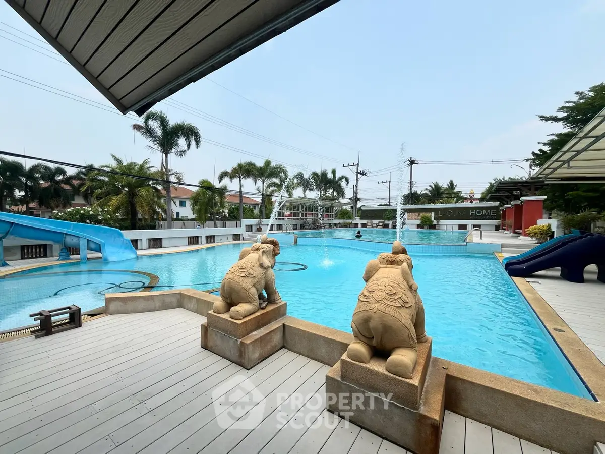 Luxurious outdoor pool area with statues and water slide, perfect for relaxation and entertainment.