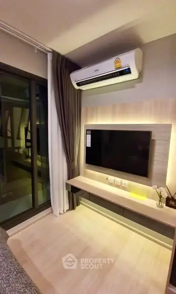Modern living room with sleek TV setup and air conditioning, featuring a balcony view.
