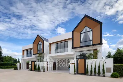 Modern architectural design of luxury townhouses with large windows and sleek lines under a clear blue sky.