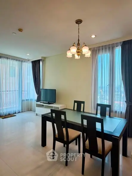 Spacious living room with elegant dining area and large windows offering natural light.