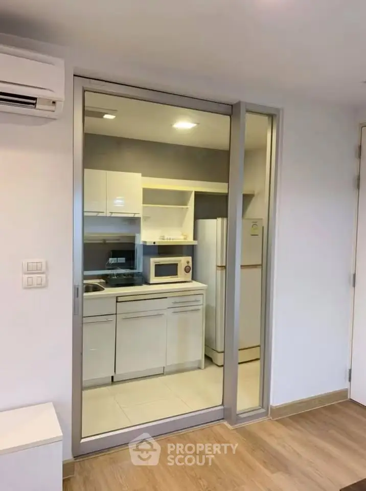 Modern compact kitchen with sleek cabinetry and appliances in a cozy apartment setting.