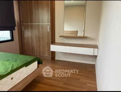 Modern bedroom with wooden flooring, built-in wardrobe, and stylish vanity mirror.