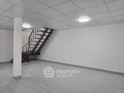 Spacious basement with modern staircase and tiled flooring, ideal for storage or conversion.