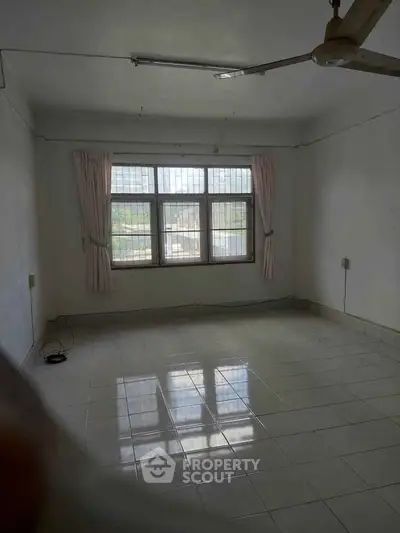 Spacious empty room with large window and tiled floor, ideal for customization.